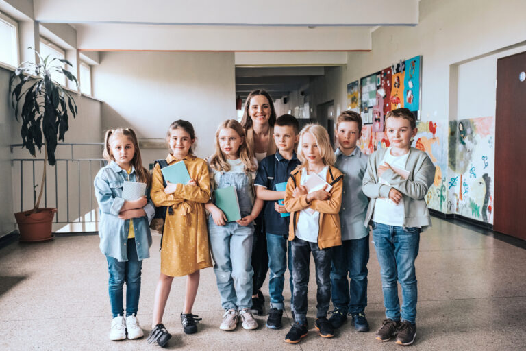 elementary school children with female teacher in a row for class photo